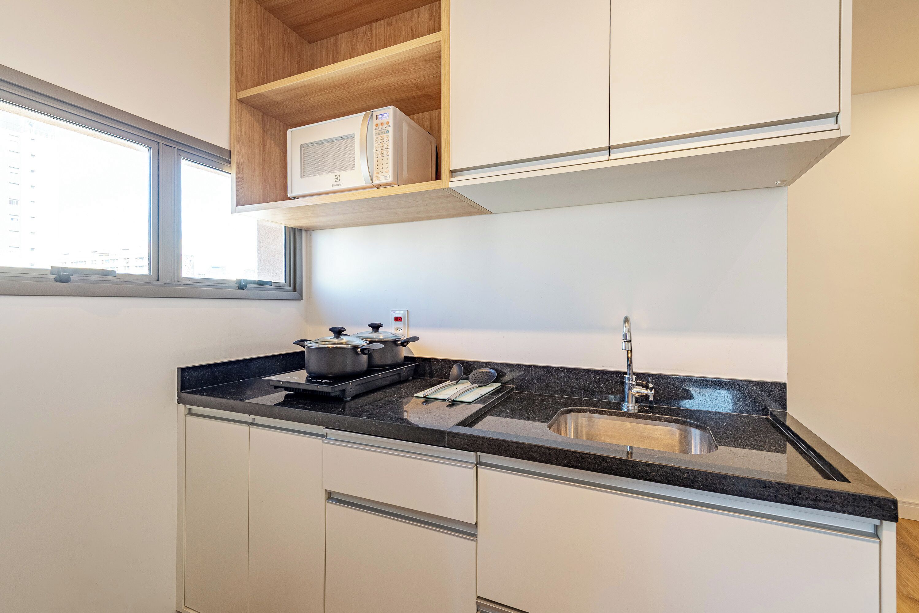 A compact kitchen with a built-in microwave, stove, and sink.