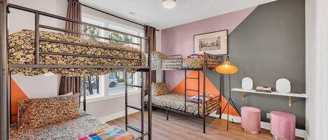 A room with bunk beds, a desk, a chair, a lamp, and a shelf with decorative items.
