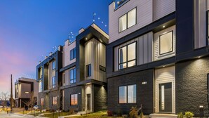 Un immeuble d’appartements moderne, avec une rangée de maisons de ville, chacune dotée d’un balcon et d’un petit jardin devant.