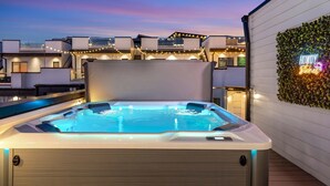 Un jacuzzi sur une terrasse sur le toit, avec vue sur les autres immeubles.