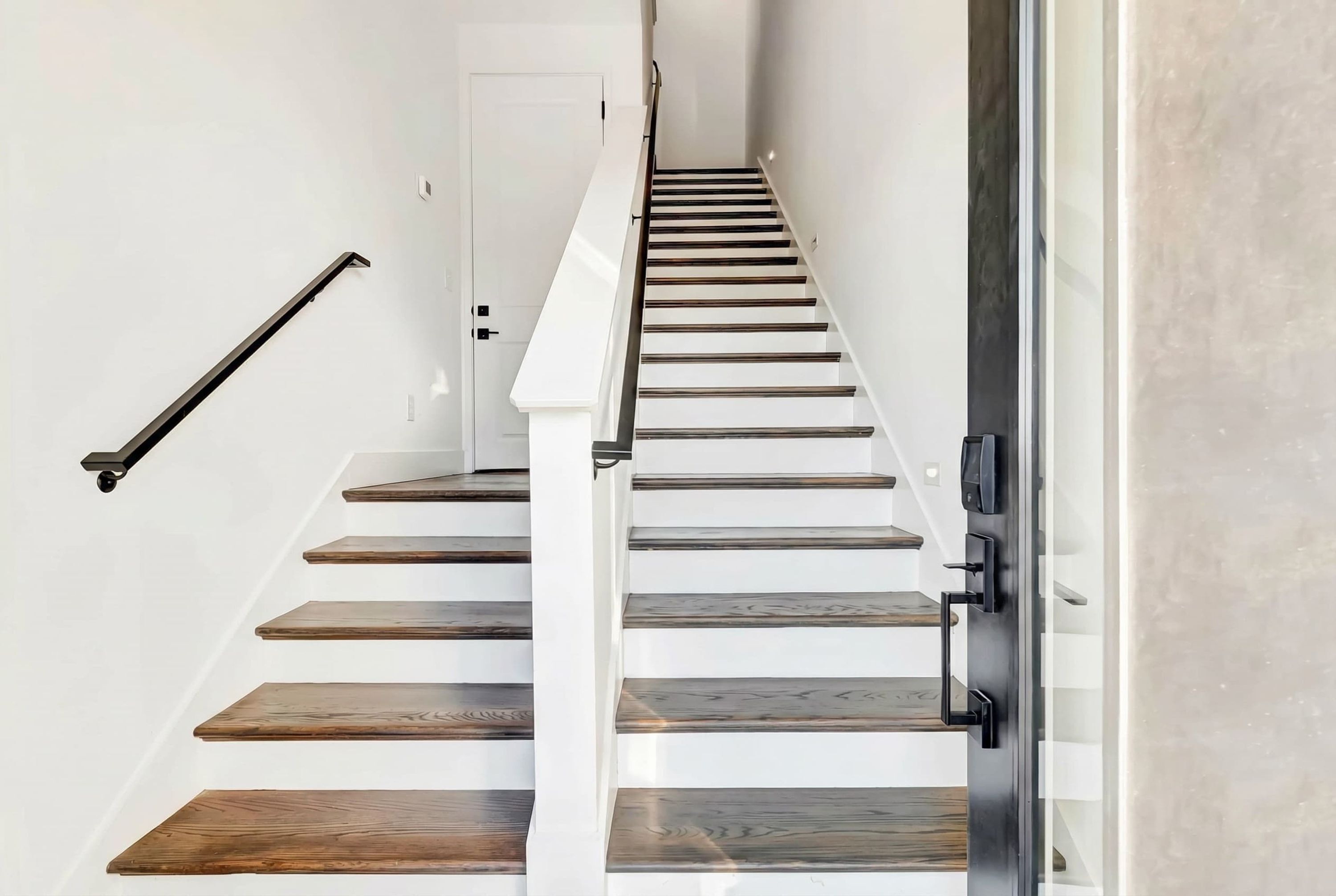 A staircase with wooden steps and a handrail, leading to a door.