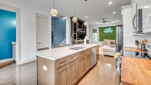 A modern kitchen with a central island, stainless steel appliances, and pendant lighting. - Rooftop Large Backyard Fire Pit Near Downtown Nashville (Nashville)
