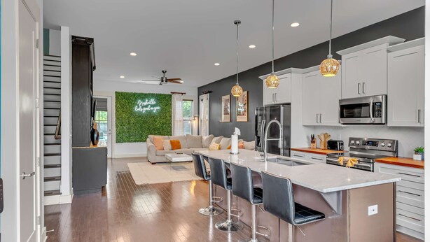 A modern kitchen with white cabinets, stainless steel appliances, and a central island with bar stools. - Rooftop Large Backyard Fire Pit Near Downtown Nashville (Nashville)