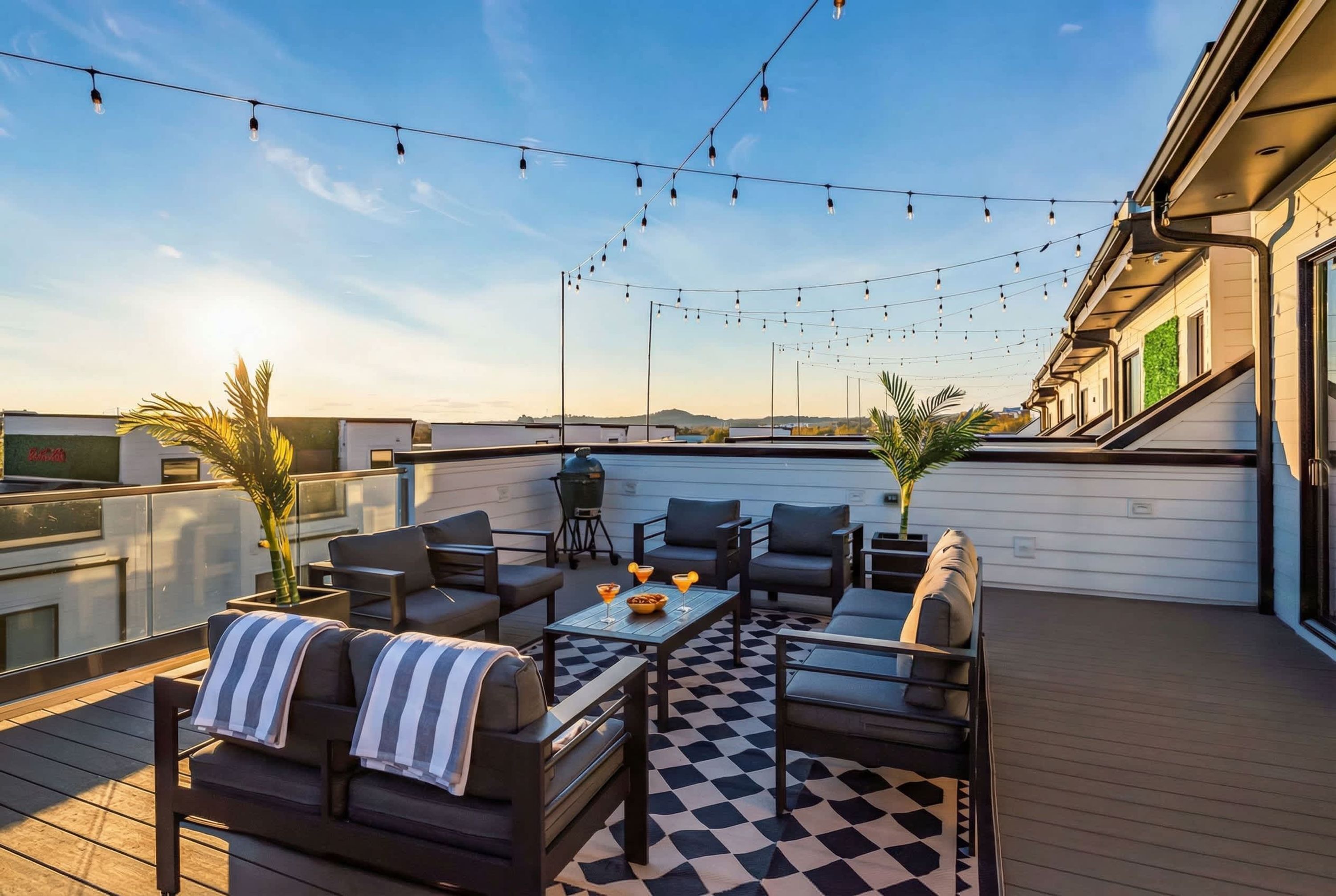 A rooftop patio with outdoor furniture, string lights, and a checkered floor.