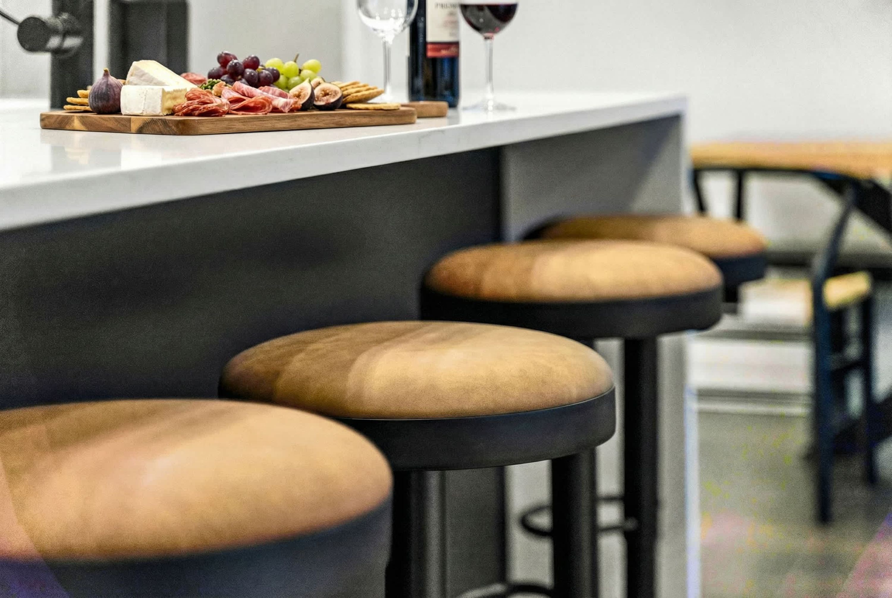 A bar area with stools and a wooden board with food and drinks.