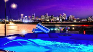 A city skyline at night with a pool area featuring a hot tub, lounge chairs, and a cocktail glass. - 2 Hot Tubs Karaoke Game Room Downtown Nashville (Nashville)
