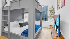 A modern bedroom with a bunk bed, a bedside table with a lamp, a TV, and a window. - Two Homes Hot Tub Rooftop Deck in Nashville (Nashville)