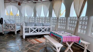 A room with a stone floor, white furniture, and a table with a pink tablecloth.