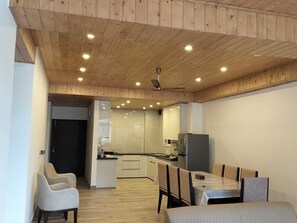 A modern kitchen with white cabinets, a refrigerator, and a dining area with a table and chairs.