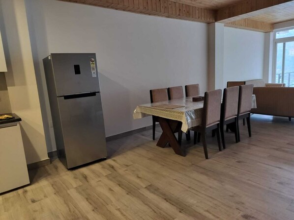 A dining area with a table and chairs, a refrigerator, and a wooden ceiling.