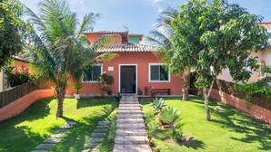 Uma casa com telhado ladrilhado, porta frontal e um caminho pavimentado que leva à entrada.
