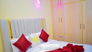 Een net opgemaakt bed met rode en witte beddengoed, een wit kussen met de tekst 'Blessings' en een rode plaid.