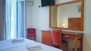 Hotellihuone, jossa on sänky, työpöytä, tuoli, televisio ja ikkuna, jossa on verhot.