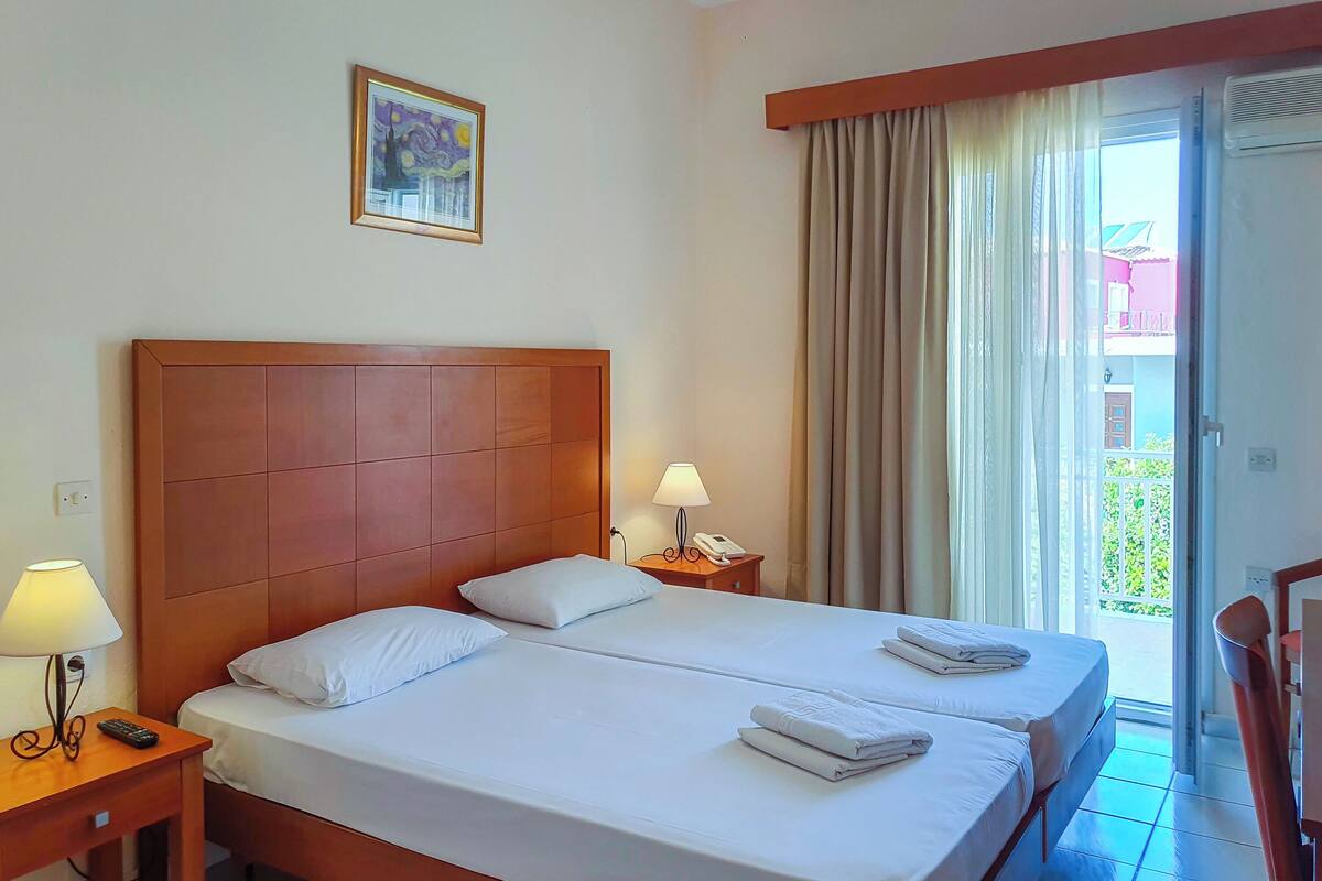Habitación de hotel con una cama grande, una mesita de noche con lámpara, teléfono y un cuadro en la pared.