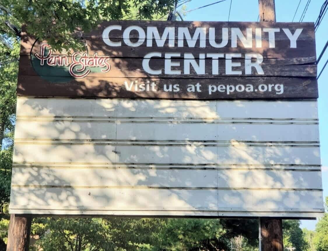 Une enseigne en bois portant l’inscription « CENTRE COMMUNAUTAIRE » et l’adresse « Visitez-nous sur pepoa.org ».