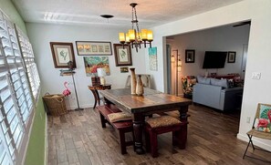 A dining area with a wooden table, benches, and a chandelier.