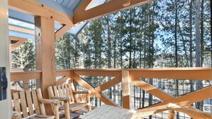 Eine Holzterrasse mit Blick auf hohe Kiefern.