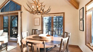 Ein Esszimmer mit einem runden Holztisch, Stühlen und einer Pendelleuchte.