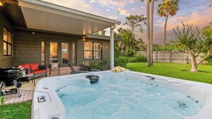 A backyard with a hot tub, outdoor furniture, and a covered patio area.