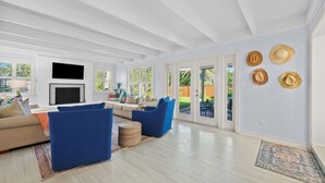 A spacious living room with a large TV, comfortable seating, and a view of the outdoors.