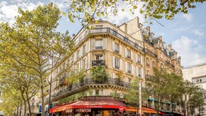 Un edificio ad angolo con un caffè chiamato 'Au P'tit Boulevard', con una tenda rossa.
