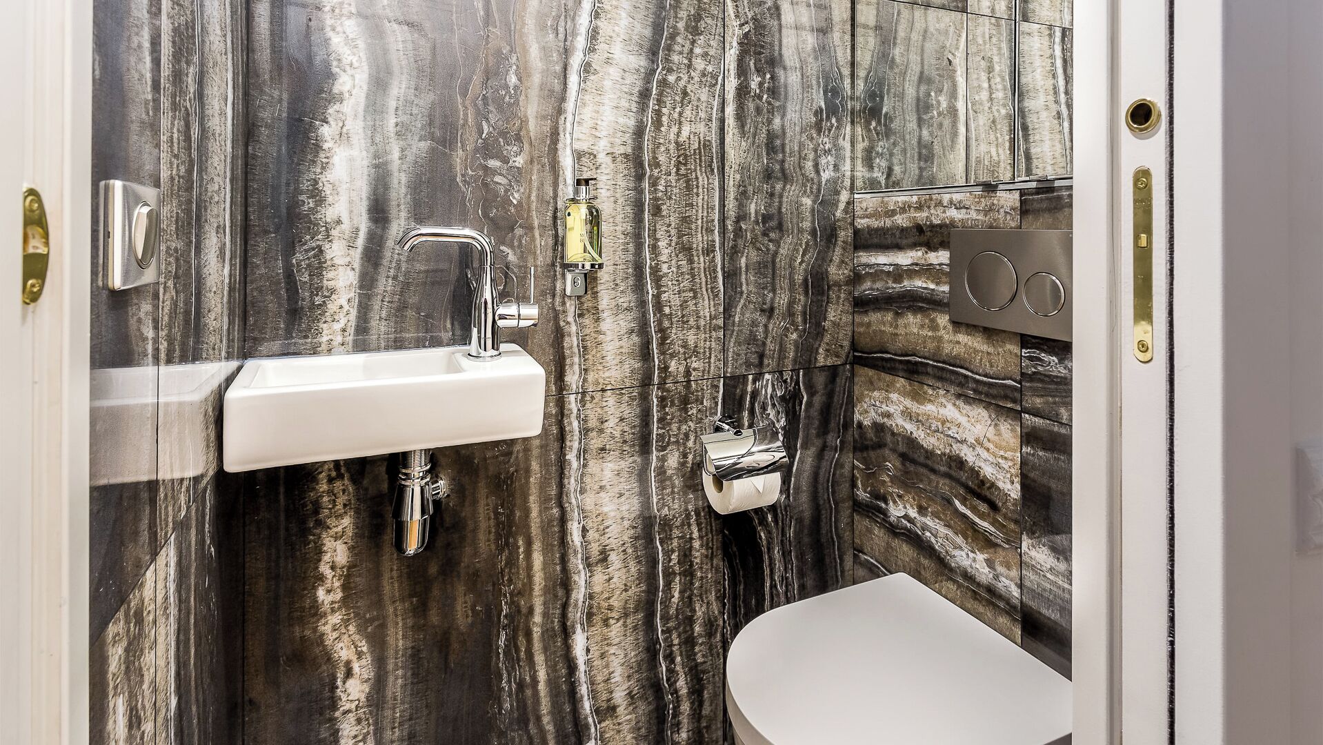 Een badkamer met een witte wastafel, een chroom kraan en een toilet.