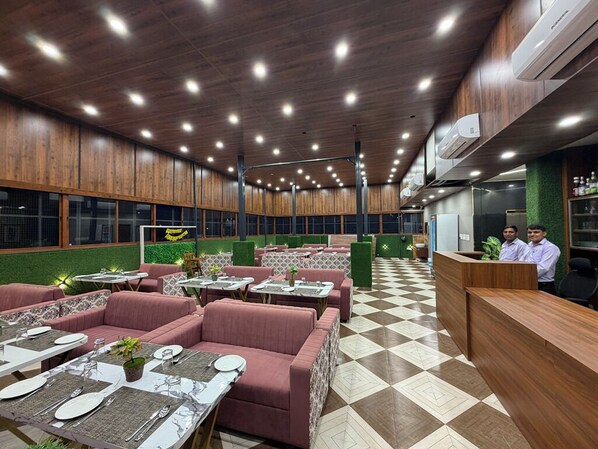 A restaurant with a checkered floor, wooden ceiling, and green walls. There are tables and chairs set up for dining.