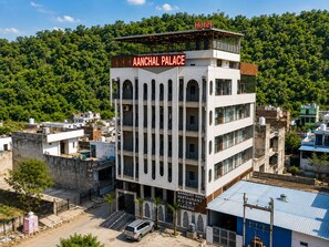 A multi-story hotel named 'AANCHAL PALACE' with a sign for 'BANQUET HALL RESTAURANT ROOMS' and 'PARKING' below.