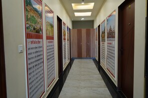 Un couloir orné d’affiches informatives sur les murs, une porte en bois au fond, et un sol en marbre.