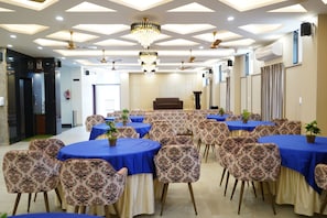 A conference room with round tables, floral-patterned chairs, and a chandelier. - Aanchal Palace Hotel  (Jaipur)