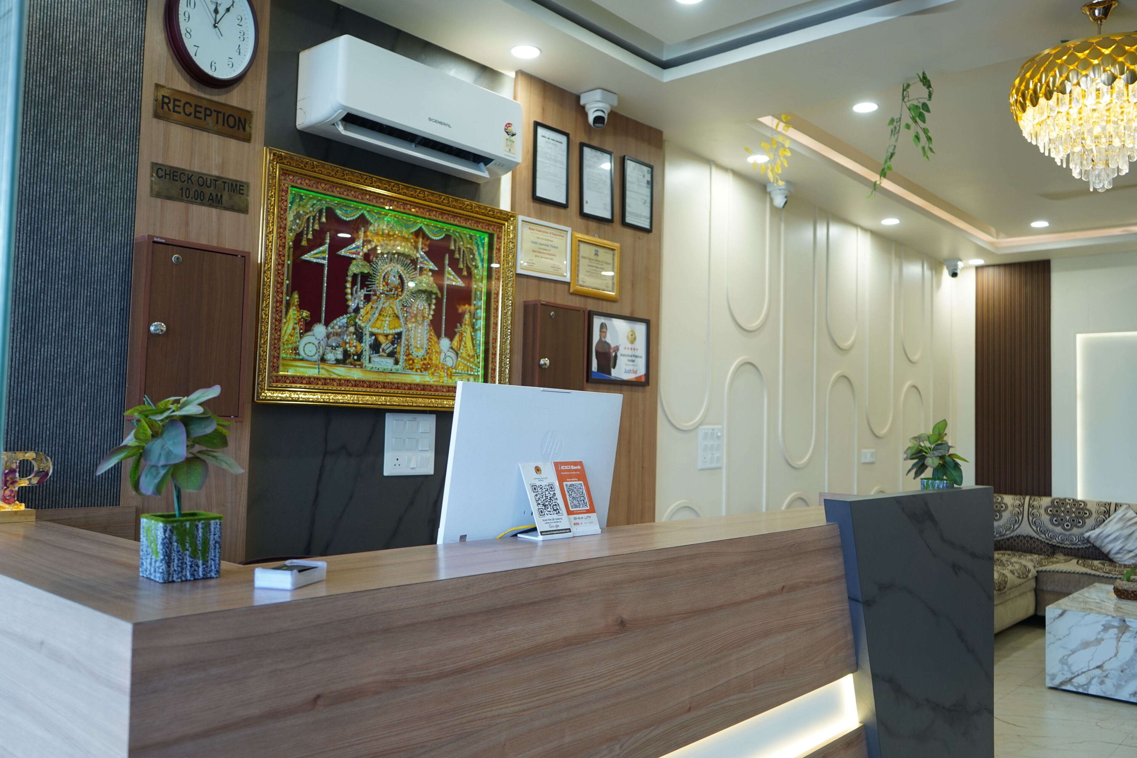 Uma receção com um relógio, unidade de ar condicionado, certificados emoldurados e um painel decorativo.