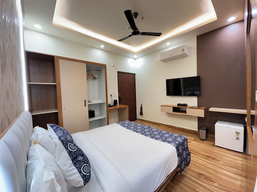 Ein Schlafzimmer mit einem Bett, einem Deckenventilator, einem Fernseher, einem Kleiderschrank und einem kleinen Kühlschrank.