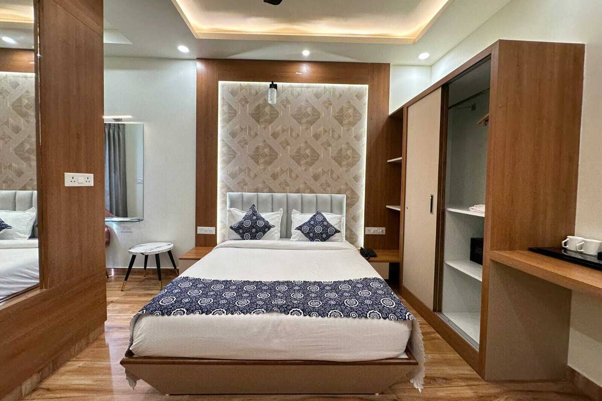 A modern bedroom with a large bed, a wardrobe, and a small table.