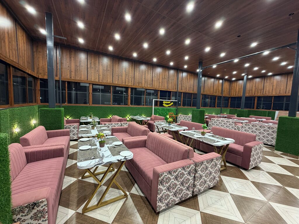 Un vaste espace intérieur aménagé avec différents coins salon, des tables et un mur végétal.