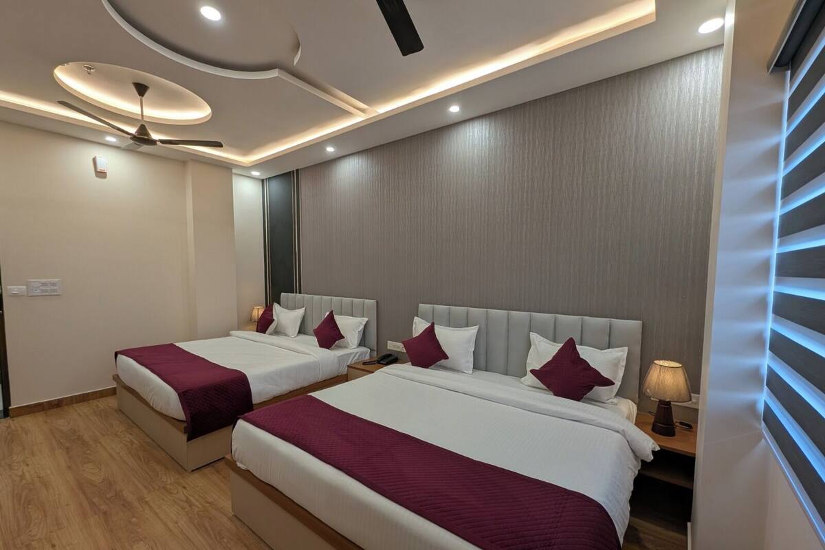 A hotel room with two beds, a ceiling fan, recessed lighting, and a wooden floor.