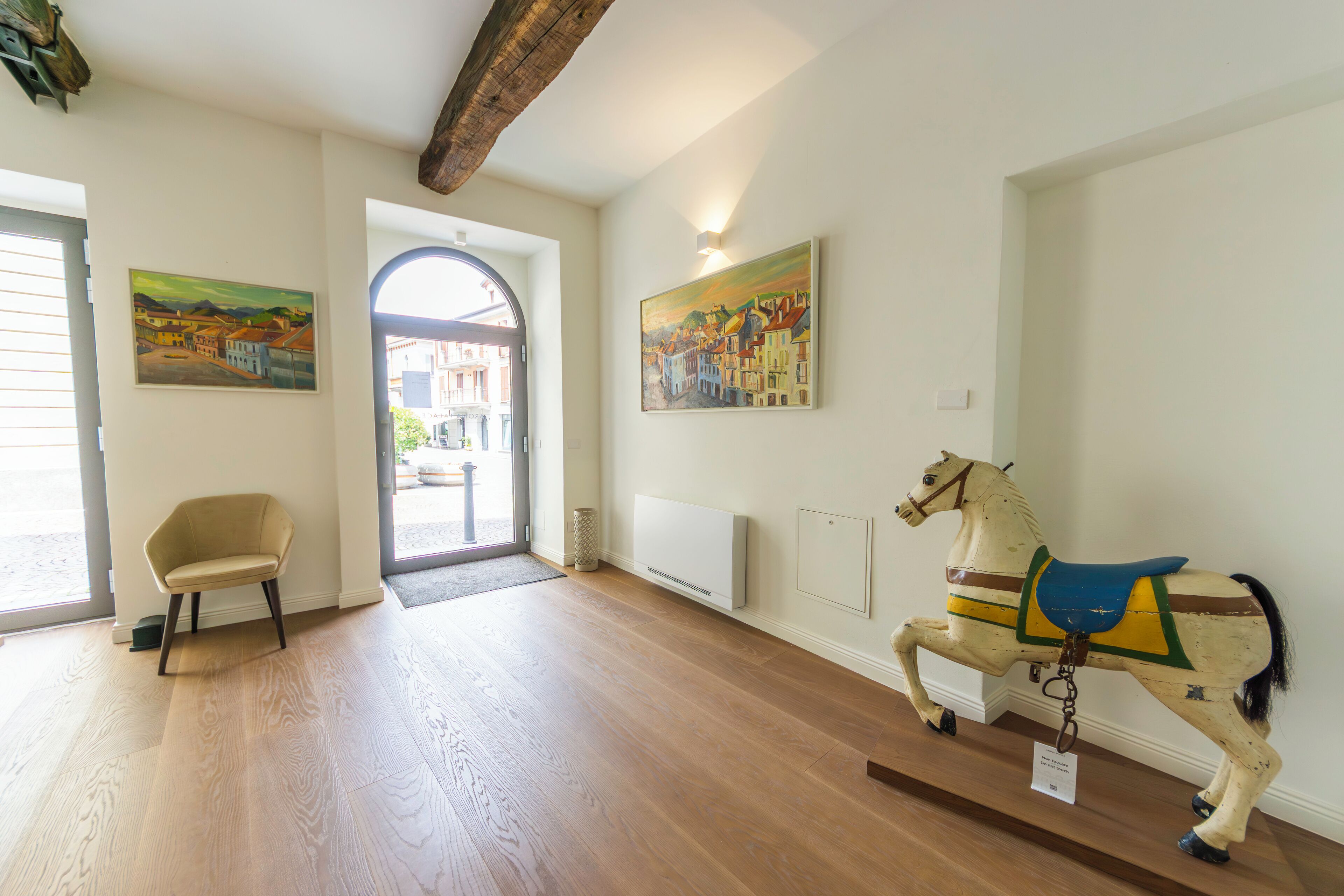 Ein Zimmer mit Holzboden, einem Sessel, einer Pfersekala und zwei Bildern an den Wänden.