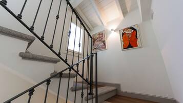 A staircase with a black metal railing, wooden steps, and a painting on the wall.