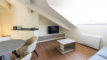 Ein modernes Wohnzimmer mit Essbereich, Flachbildfernseher und Kamin.