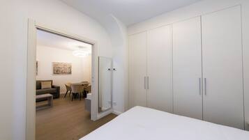 A bedroom with a large bed, a wardrobe, and a bathroom with a shower.