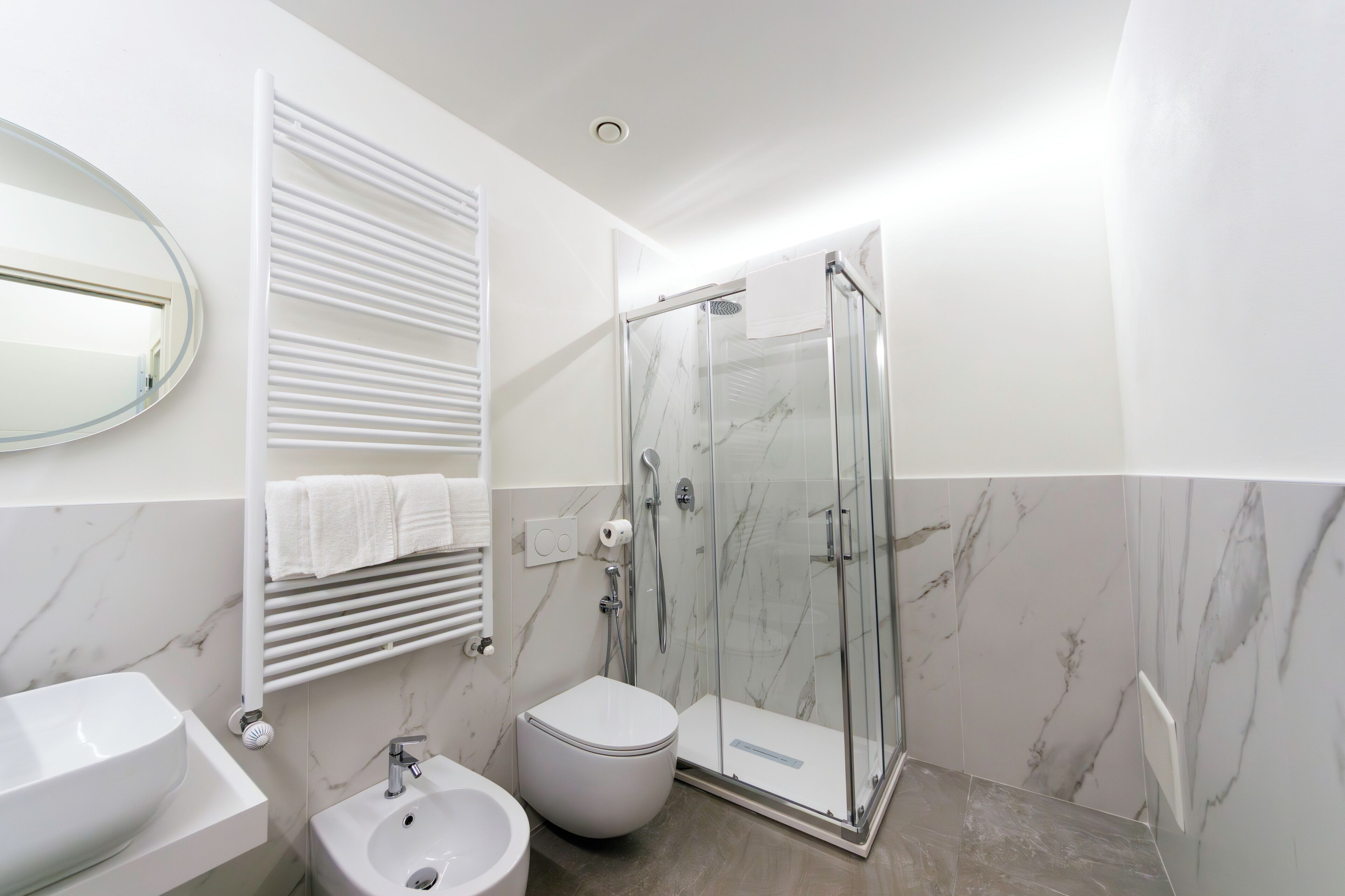 Une salle de bain moderne avec une douche à parois de verre, un lavabo blanc et des toilettes.