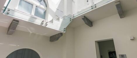 Een meerlaags interieur met glazen balustrades, een dakraam en een modern architectonisch ontwerp.