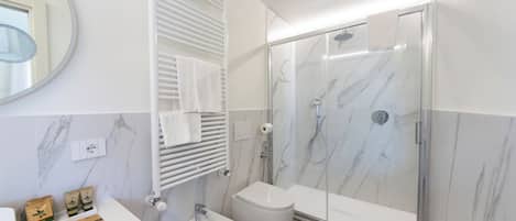 Un baño moderno con ducha de mármol, un bidé y un lavabo blanco.