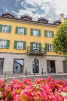 Un edificio amarillo con contraventanas verdes y un balcón.