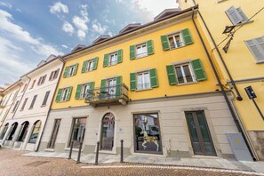 Eine Reihe bunter Häuser mit grünen Fensterläden, eine gepflasterte Straße und ein klarer, blauer Himmel.