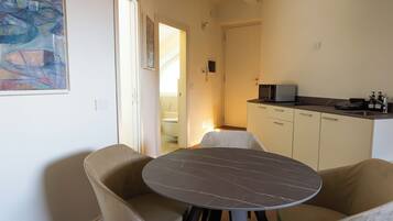 A modern kitchen with white cabinets, a black countertop, and a dining area with a round table and two chairs.