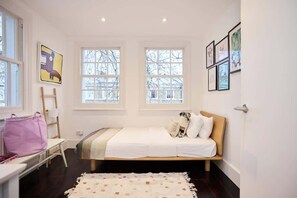 A bedroom with a bed, windows, a desk, and a chair.