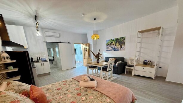 A bedroom with a floral bedspread, a desk, a chair, and a ladder against the wall.
