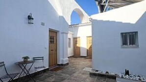 A courtyard with white walls, a tiled floor, and a small table with chairs.