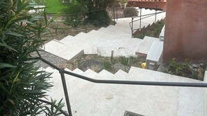 Eine Treppe führt zu einem Gebäude mit einem Ziegeldach, umgeben von Grün und mit freiem Blick auf die Landschaft.