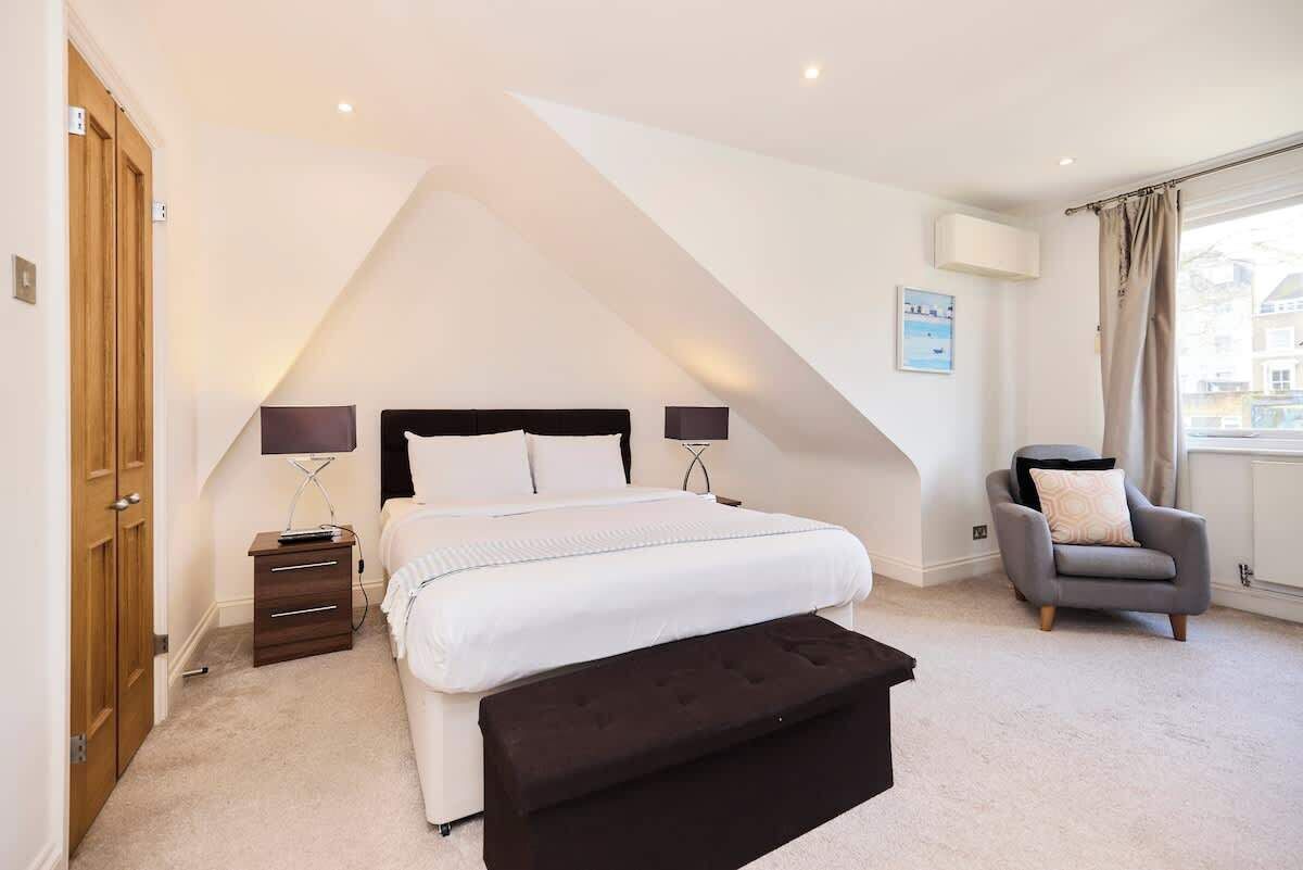 A bedroom with a bed, bedside tables, a chair, and a window.